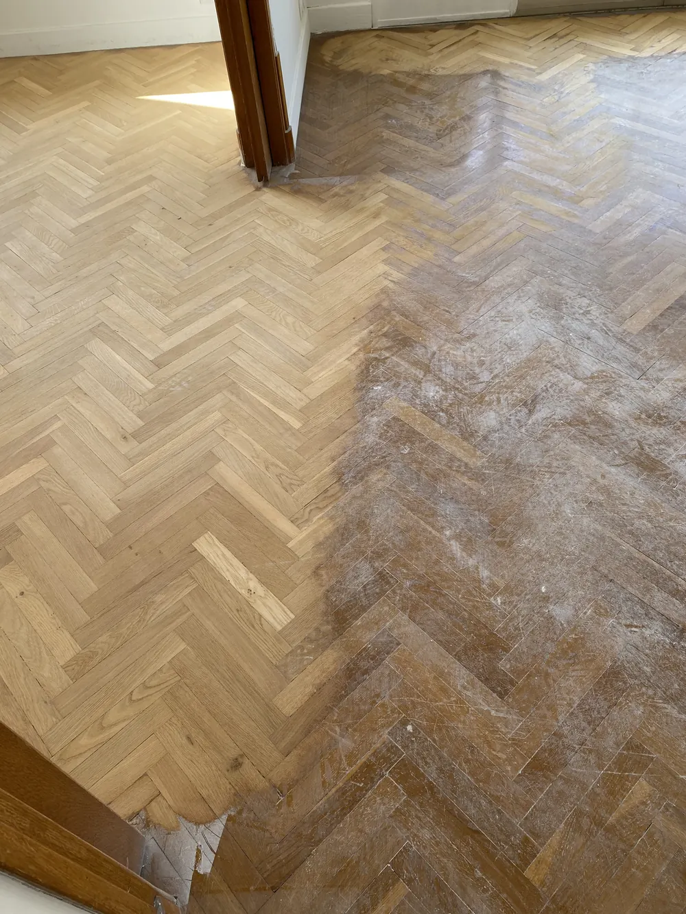 Parquet à bâton rompu, ponçage en cours : la moitié gauche est poncée, la droite est dans son état d'origine